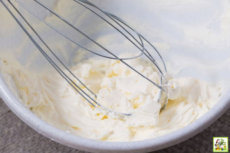 Whisk mixing softened cream cheese in a bowl.
