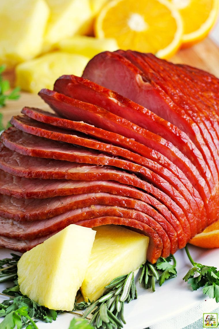 Closeup of a spiral cut Spiral Instant Pot Ham on a white ceramic platter with pineapple slices.