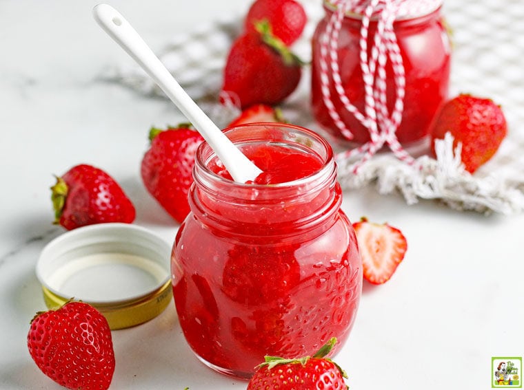 Jars of Keto Strawberry Sauce with a serving spoon and strawberries.