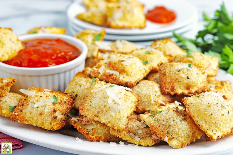 Closeup of a plate of fried air fryer ravioli and a ramekin of marinara sauce.