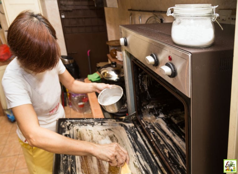 Woman brushing on baking soda paste in a dirty oven to clean it.