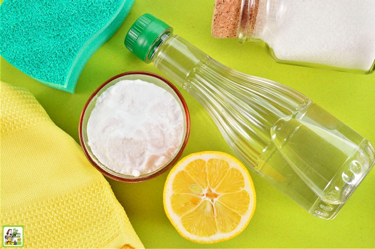 Materials for cleaning oven including baking soda, vinegar, lemon, salt, cleaning rags, and sponge.