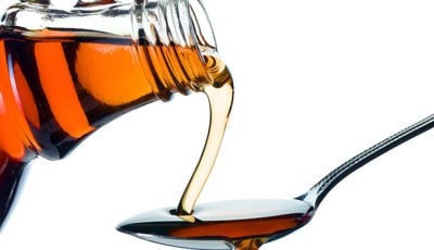 Maple syrup being poured from a bottle on to a spoon.