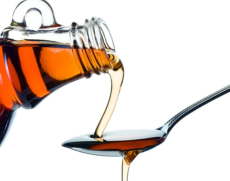 Maple syrup being poured from a bottle on to a spoon.