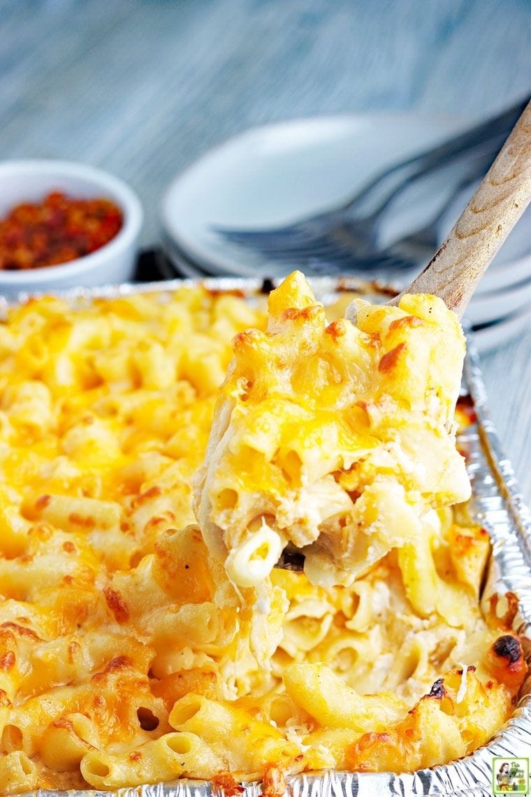 Spooning up a serving of smoked macaroni and cheese from an aluminum casserole dish.