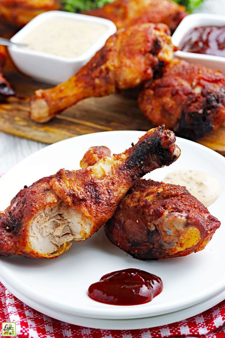 A white plate with two BBQ chicken legs with a bite taken out of one.