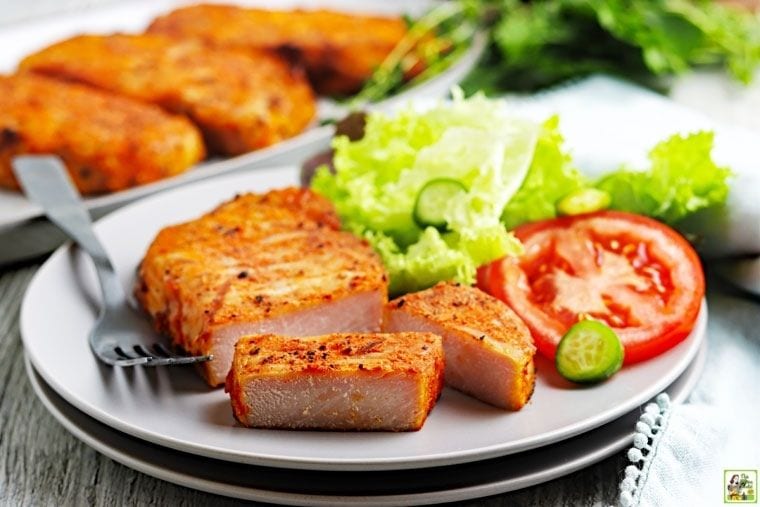 Traeger smoked pork chops on a plate with fork, lettuce, and sliced tomato.