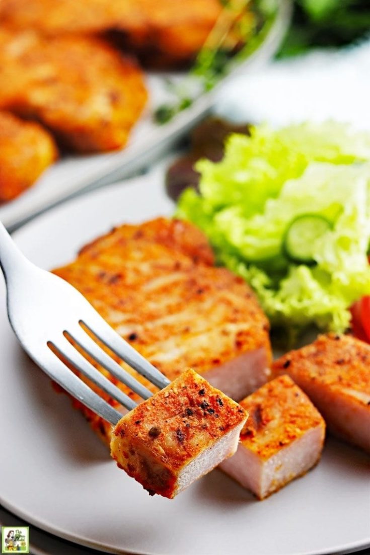 A forkful of sliced smoked pork chops on a plate with lettuce.