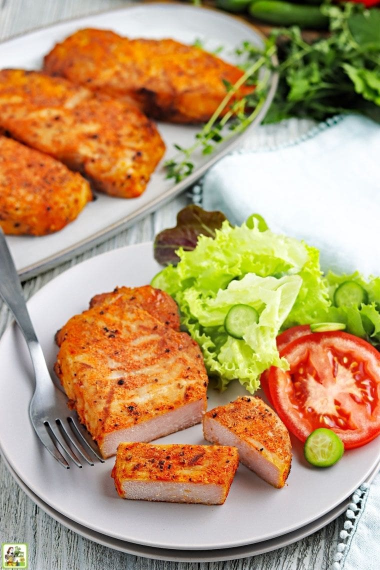 Plate and platter of cooked smoked pork chops with garnish of lettuce and tomato.