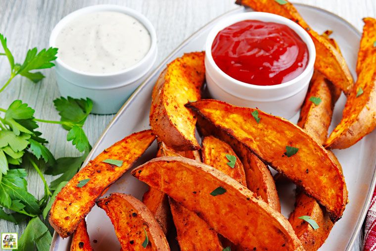 A platter of air fryer sweet potato wedges with small bowls of dipping condiments.